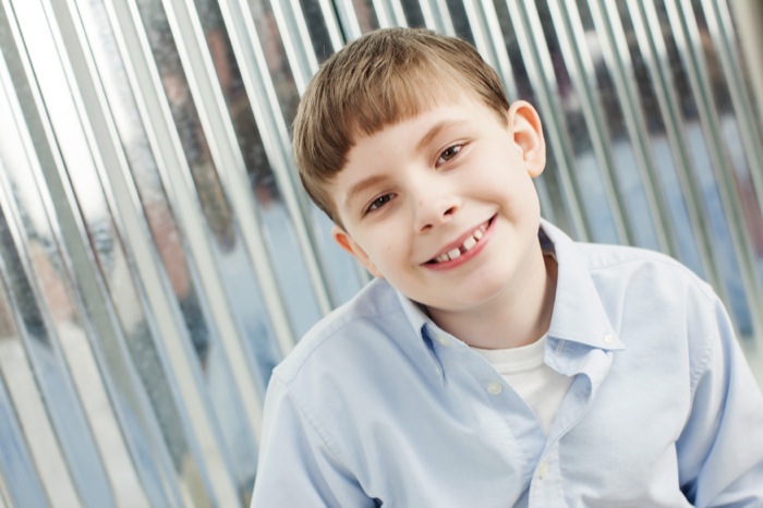 Smiling young boy with braces wearing a light blue shirt.