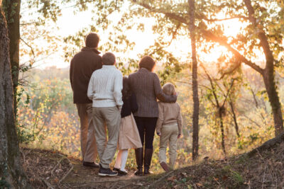 Family of five walking together in an forest during sunset.