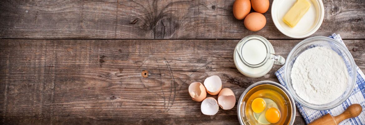 Eggs, milk, and cracked shells on a rustic wooden surface.