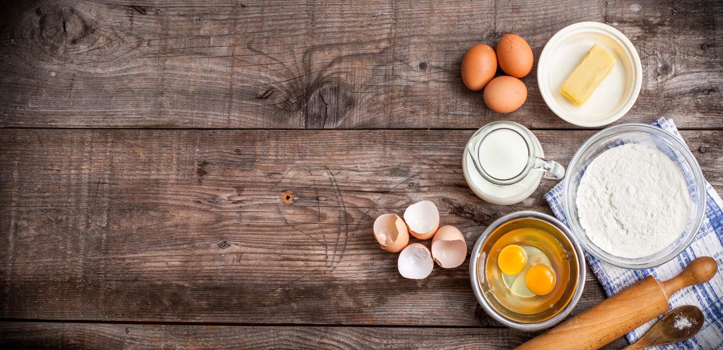Eggs, milk, and cracked shells on a rustic wooden surface.