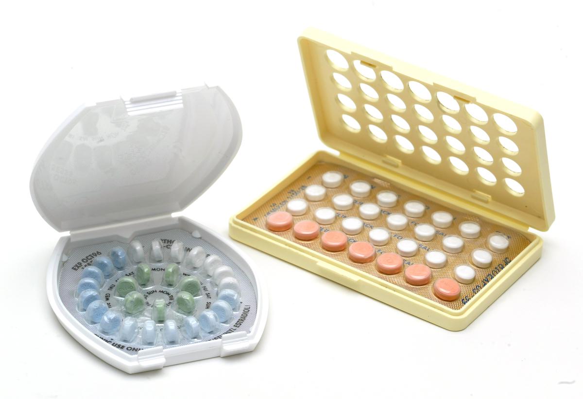 Two open birth control pill packs with different designs and colored pills.