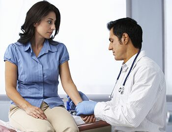 Doctor examining patient's arm in a clinical setting.
