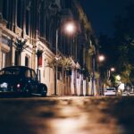 A vintage car parked on a quiet, dimly lit street at night.