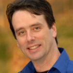Portrait of a smiling man in a blue shirt outdoors.