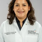 A smiling female doctor in a white coat with Hartford HealthCare logo.