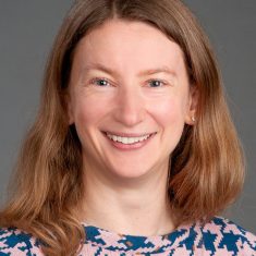 Smiling woman with shoulder-length hair in a floral top.