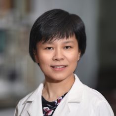 Professional woman in a white lab coat smiling.