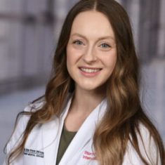 Young female doctor smiling in white coat.