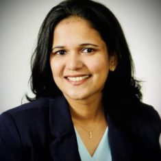 Smiling professional woman in a dark blazer and light blue top.