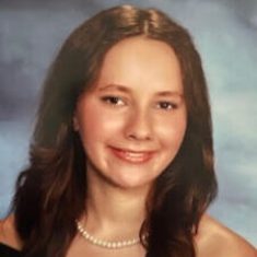 Young woman smiling in a formal portrait with a pearl necklace.